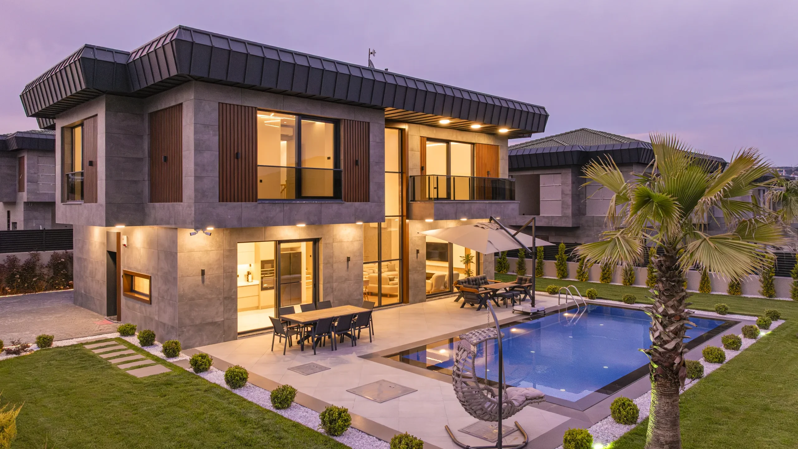 Garden İstanbul villasının akşam görünümü; cam cephe, teras ve havuz