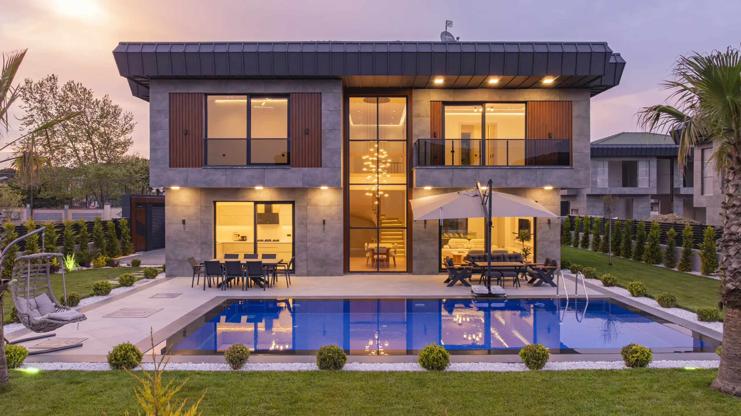 Garden İstanbul örnek villası gün batımında; aydınlatılmış cephe ve özel havuz